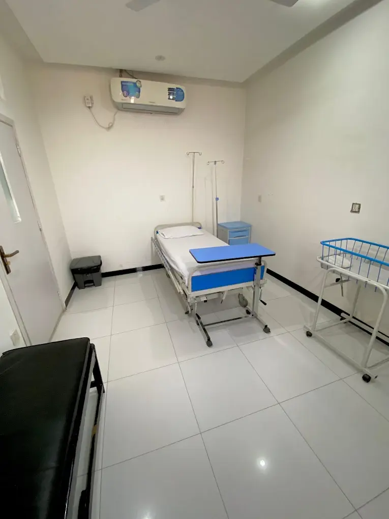 Single patient care room with a made bed, an overbed table, a bedside cabinet, an IV stand and an air conditioner.